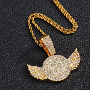 Macro shot of gold hip-hop necklace with iced-out wing pendant on black leather