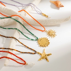 Colorful beaded stainless steel necklaces with gold pendants on a white starfish