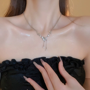 Detail of silver butterfly necklace with pearls and rhinestones on woman's neck
