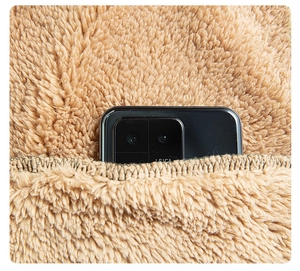 Dettaglio della giacca in pile color cammello che mostra la tasca profonda con smartphone