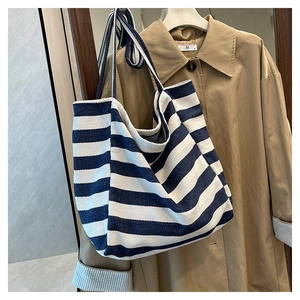 Blue and white striped canvas tote bag styled with a trench coat on a hanger