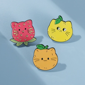 Detailed close-up of cute cartoon cat enamel pins featuring strawberry and citrus fruits