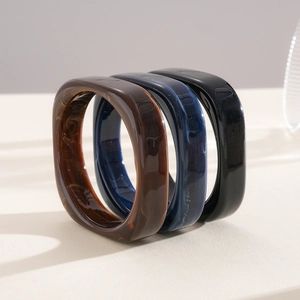 Close-up of resin square bangles with marbled texture in brown, blue, and black