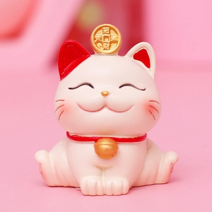 Lucky cat car ornament with gold coins and red collar on soft pink background
