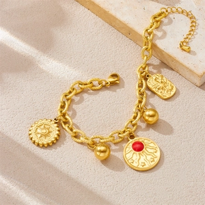 Detail view of gold stainless steel bracelet with sun motifs and red gemstone charm
