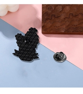 Detail view of the black enamel pin's textured back and metallic butterfly clutch fastener