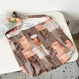 Detail of floral oil painting tote bag with vintage brown patchwork on a white desk