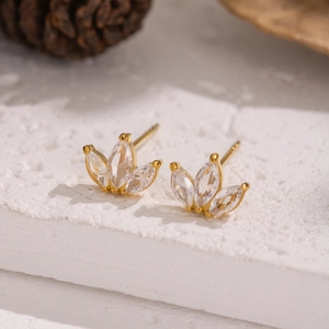 Detailed view of gold clover stud earrings with clear zircon stones on a natural background