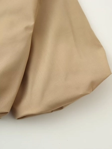 Détail du tissu sergé kaki montrant la texture premium et le pli structuré de la jupe