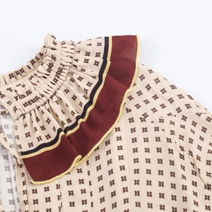 Detailed view of ruffle collar with yellow piping and brown geometric patterns