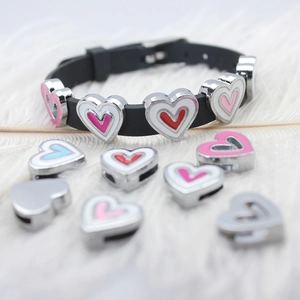 Detail of colorful enamel heart charms on 8mm black wristband over soft white feathers