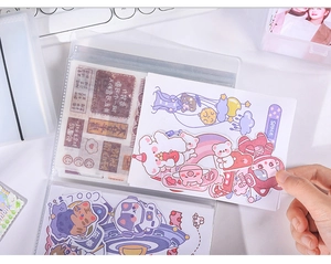 Detail of high-capacity transparent binder storing cartoon stickers and cards on a desk