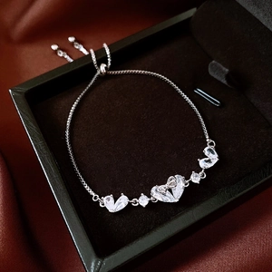 Detail of adjustable silver heart bracelet with cubic zirconia on black velvet and satin