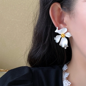 Close-up of elegant white flower stud earring with gold center on model's ear