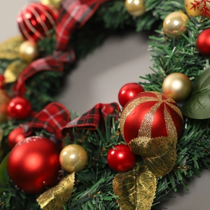 Christmas wreath featuring red and gold ornaments with black-red plaid ribbon decoration