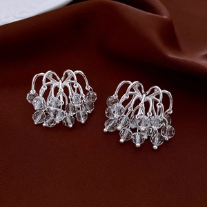 Detail of silver heart tassel earrings with crystal beads on brown satin fabric