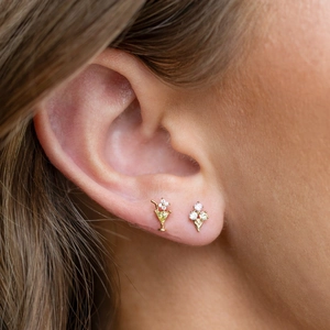 Close-up of gold-plated cocktail and ice cream studs with sparkling zircons on ear