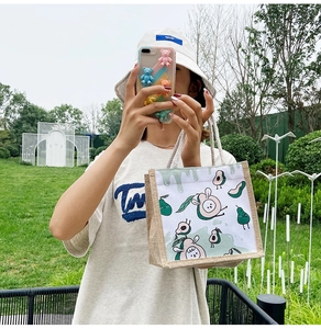 Detailed view of linen tote bag with cute cartoon avocado prints and rope handles