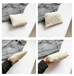 Detail view of white quilted clutch bag with floral petal texture and soft compact design