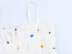 Dettaglio del tessuto in rete bianca con pois 3D colorati e spalline regolabili
