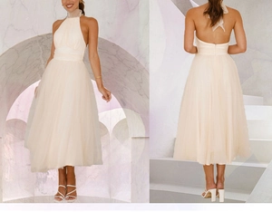 Detail view of beige halter mesh dress showing front and back design against stone arch