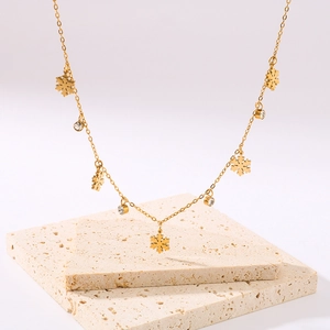 18K gold plated necklace featuring snowflake charms and rhinestones on stone background
