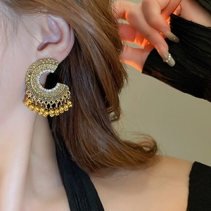 Ethnic retro gold-finished hoop earrings with fringe beads shown on a model
