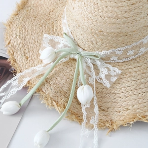 Straw sun hat with white lace trim, green bow and tulip pendants for beach vacation