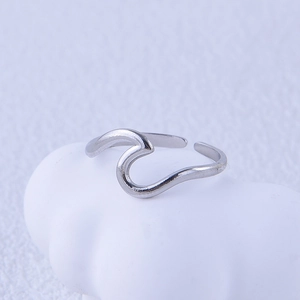 Detail of minimalist wavy stainless steel open ring on a textured artistic background