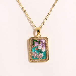 Detailed shot of an enamel floral pendant with fresh water pearl and crystal frame