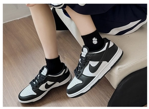 Close-up of black and white leather sneakers featuring small panda embroidery detail