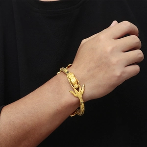 Detail of a golden dragon head bracelet in 18k gold plating on a male wrist