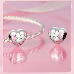 Macro view of heart-shaped S925 silver bead with couple kissing and pink enamel detail