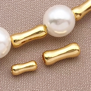 Vista macro di perline a tubo di bambù placcate oro 18k e perle bianche per gioielli DIY
