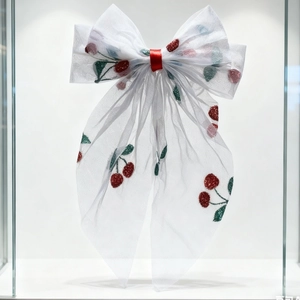 Close-up of white mesh bow hair clip featuring red cherry embroidery detail on organza