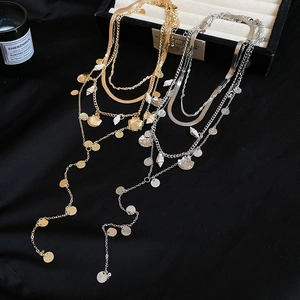 Close-up of bohemian layered necklaces with metal shell charms and round sequins