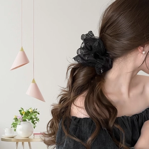 Detailweergave van een elegante oversized zwarte kanten scrunchie gedragen in het haar