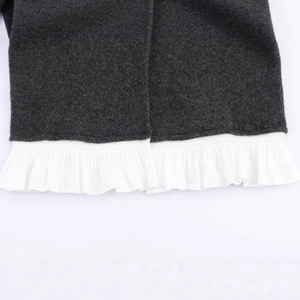 Dark grey knit jacket with white poplin ruffled hem detail in a layered aesthetic