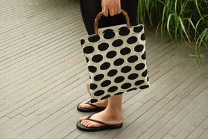 Detail of bamboo handle on a retro cream fabric handbag with bold black polka dots
