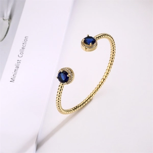 Detail of gold cuff bracelet featuring blue round gemstones and micro-pave accents