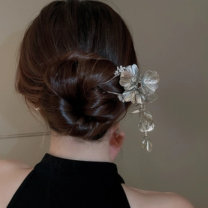 Close-up of a silver flower hair stick with elegant tassels and diamond accents on a bun