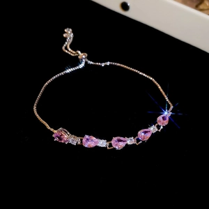 Detail of pink teardrop zircon stones and rose gold chain on a black velvet base