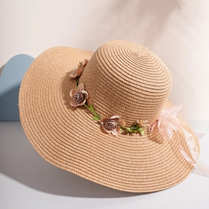 Close-up of beach straw hat with realistic rose floral wreath and organza ribbon