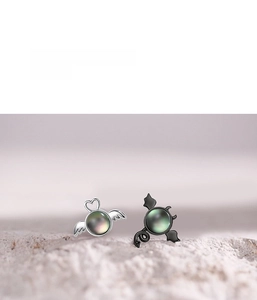Detail of asymmetric angel and demon earrings with black opal inlay on textured stone