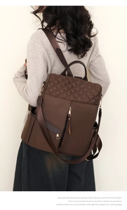 Detail of dark brown nylon backpack featuring diamond-quilted stitching and gold zippers