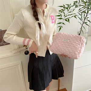Détail de la trousse de toilette matelassée rose à fleurs tenue dans un cadre intérieur
