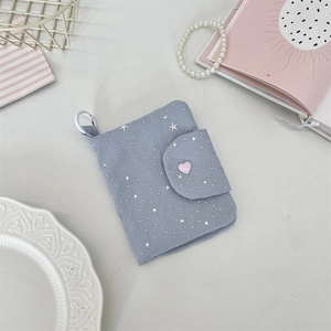Close-up of light blue fabric card holder with star patterns and pink heart button