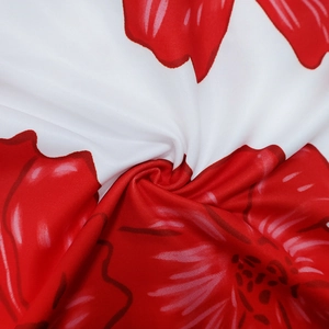 Close-up of white fabric with vibrant red floral print and smooth, silky texture details