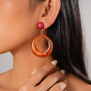 Vue détaillée des boucles d'oreilles clips en résine vintage avec anneau ambre et perle rouge