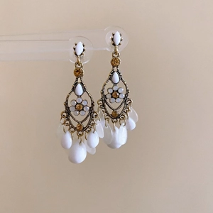 Vue détaillée des boucles d'oreilles à pompon rétro avec pierres en résine blanche